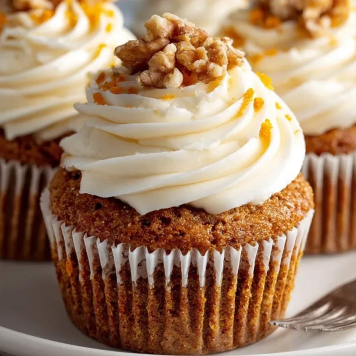 Close-up of a frosted Carrot Cake Cupcake, walnuts sprinkled on sweet cream cheese.