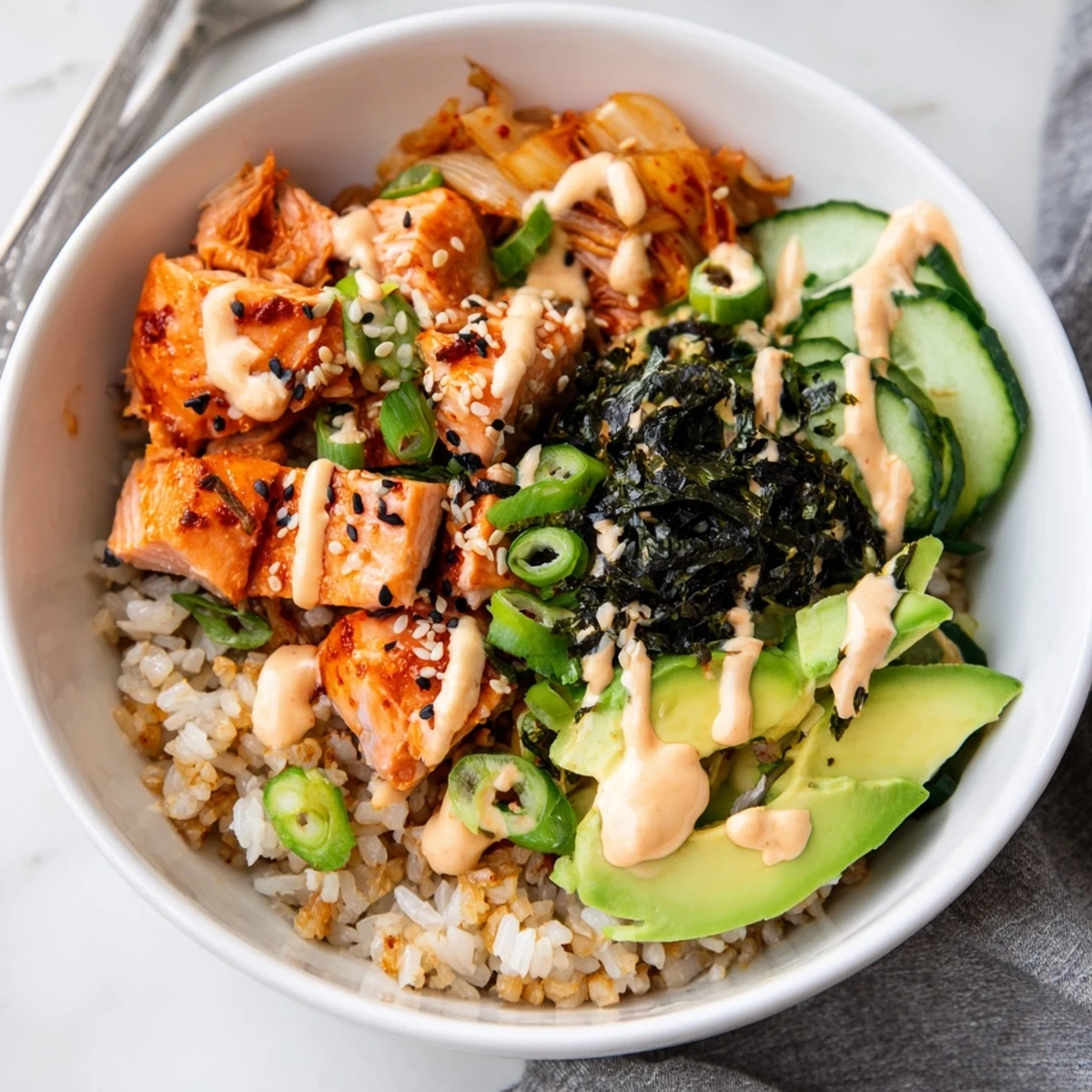 Crispy Salmon Rice Bowl topped with spicy mayo, kimchi, and fresh avocado slices.  