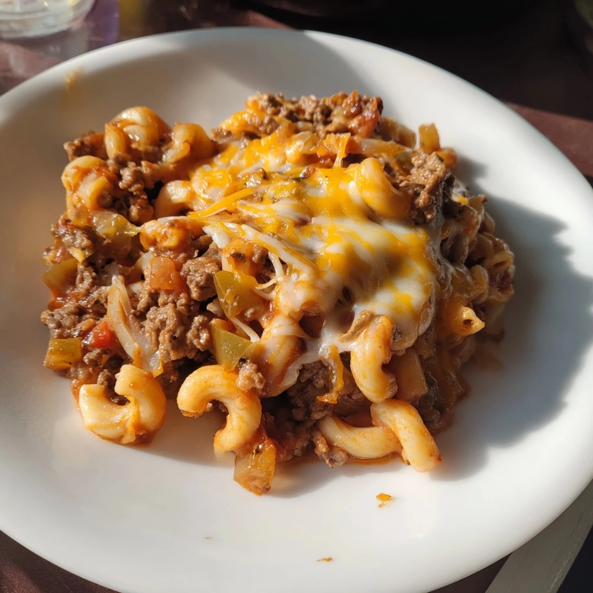 Steaming hot hamburger casserole with melted cheddar, perfect for a cozy family dinner tonight.