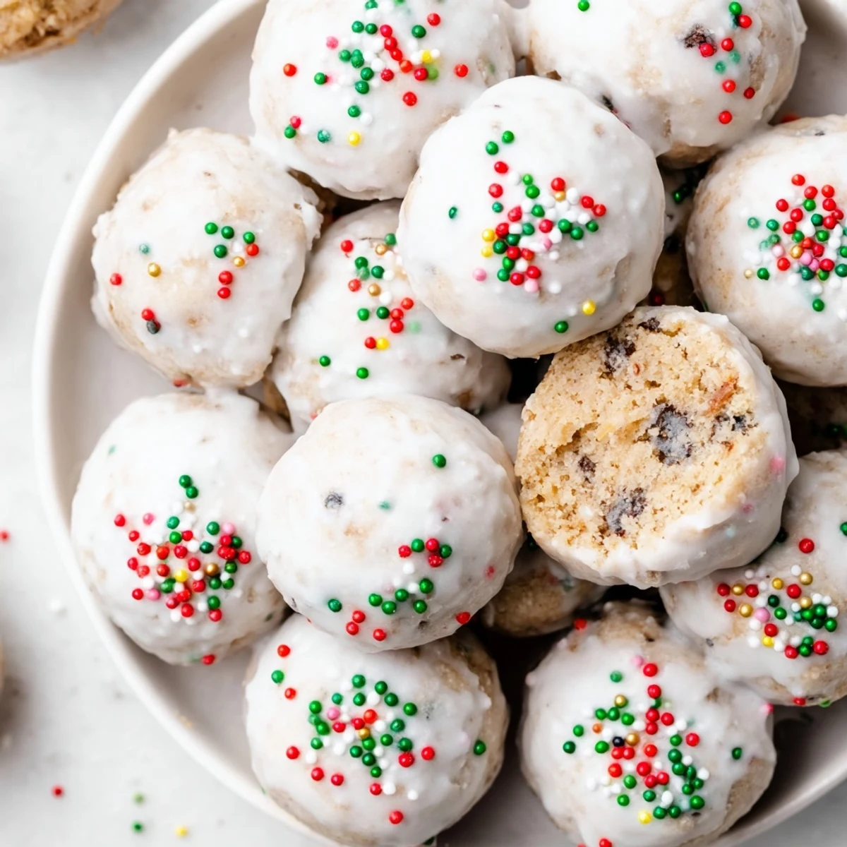 Close-up of Protein-Packed Italian Christmas Cookie Balls, drizzled in white glaze and covered in festive sprinkles.