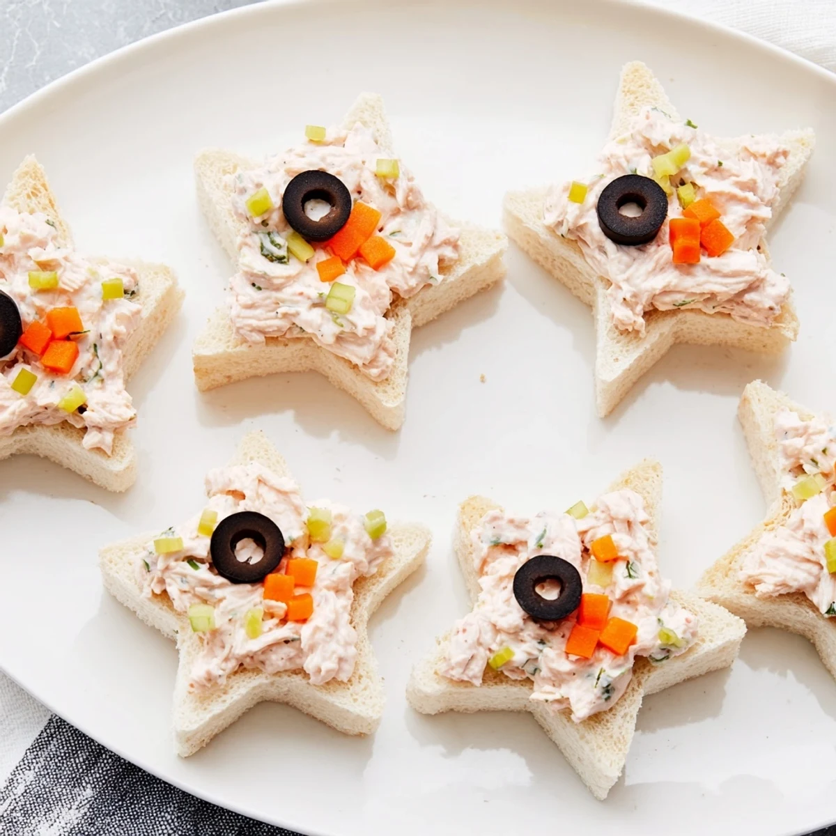 Mini Starfish Sandwiches shaped with olives and capers, ready to serve at a themed party.