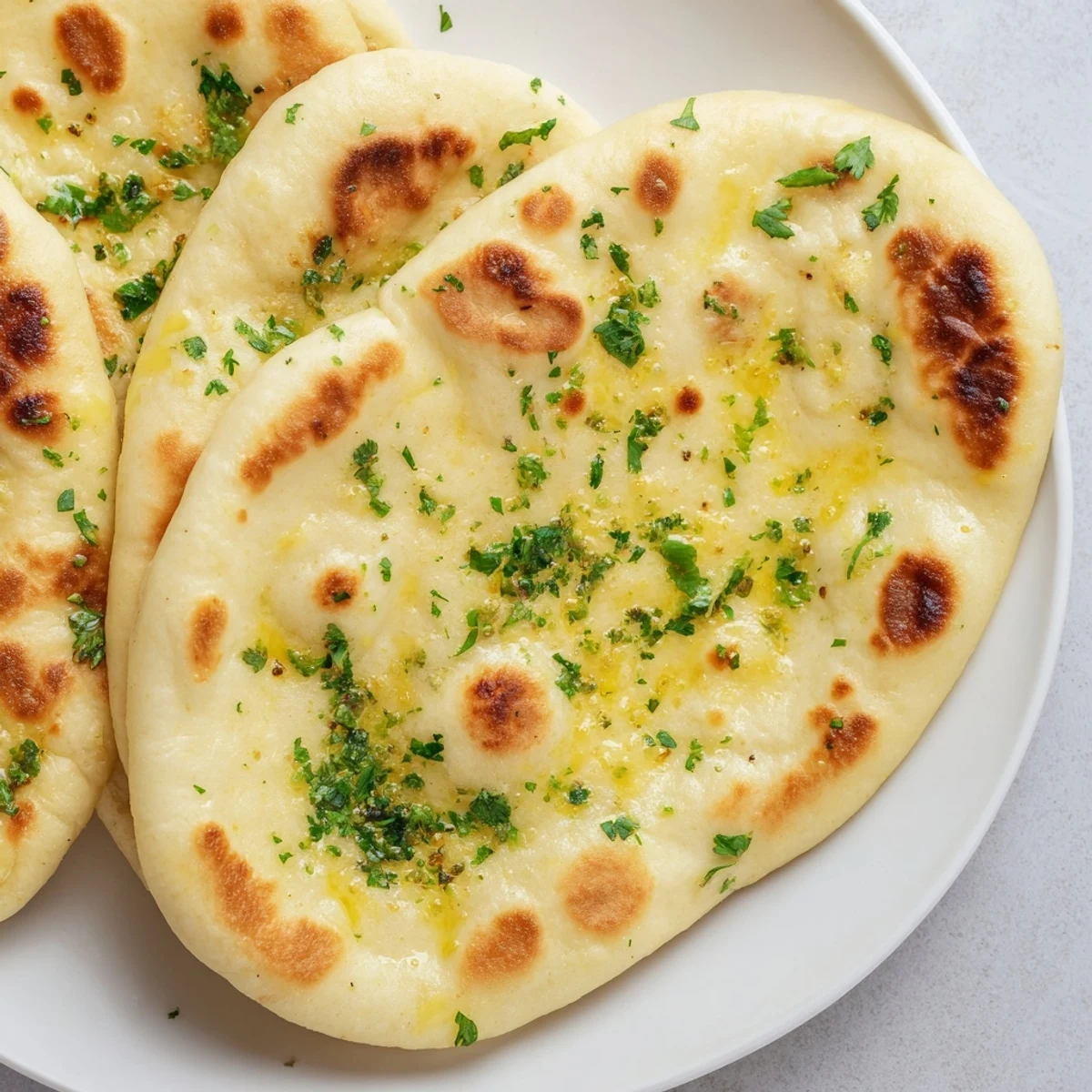 Warm, soft Homemade Garlic Naan Bread, with visible golden bubbles and fragrant garlic scent, ready to serve.