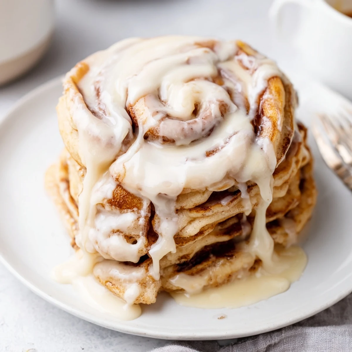 Golden, fluffy Cinnamon Roll Pancakes drizzled with sweet cream cheese frosting, a decadent breakfast.