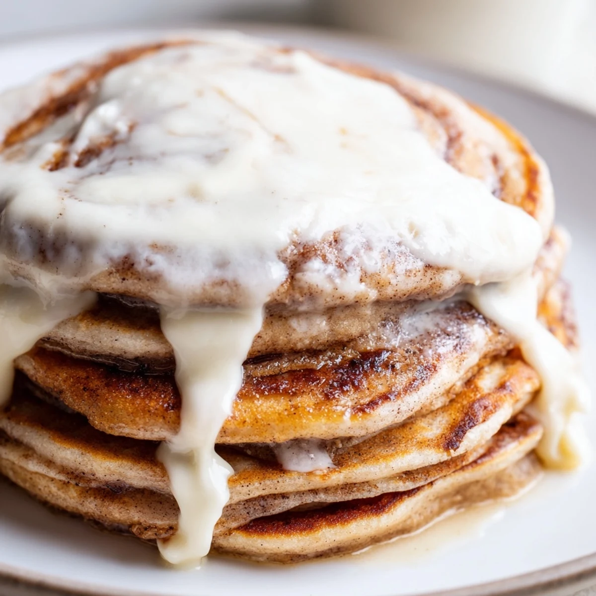 A stack of warm Cinnamon Roll Pancakes, swirled with cinnamon, offers a comforting, sweet morning treat.