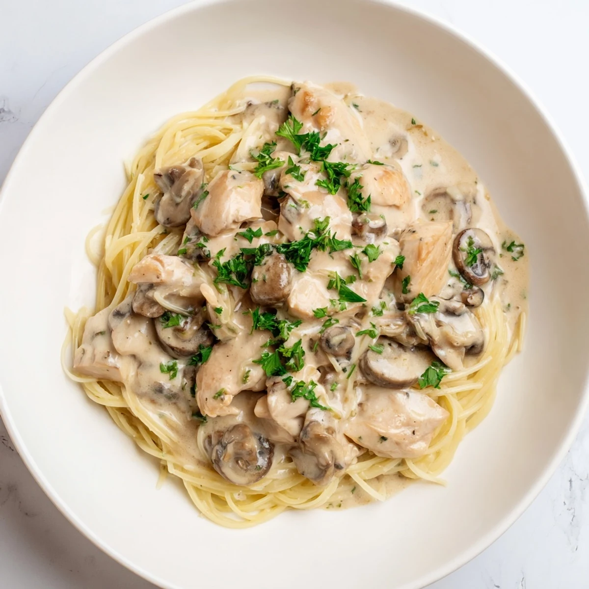 Creamy Mushroom Chicken Spaghettini features tender chicken strips and al dente pasta coated in a velvety mushroom cream sauce garnished with fresh parsley.