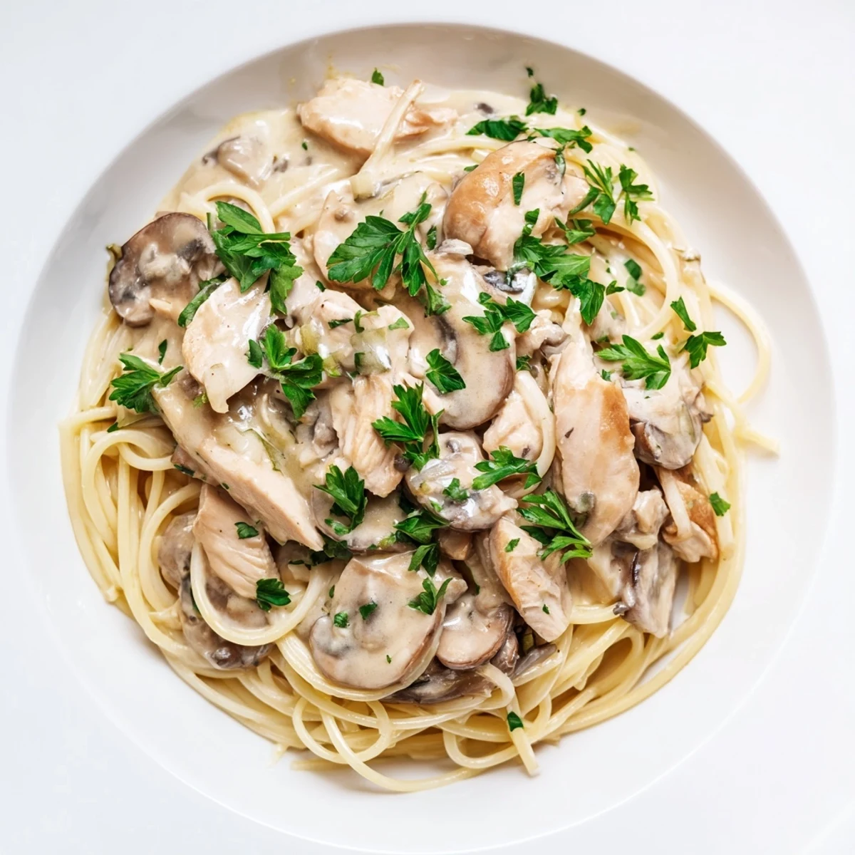 Savory Creamy Mushroom Chicken Spaghettini plated with golden seared chicken and sautéed mushrooms in a light, glossy cream sauce, ready to serve.