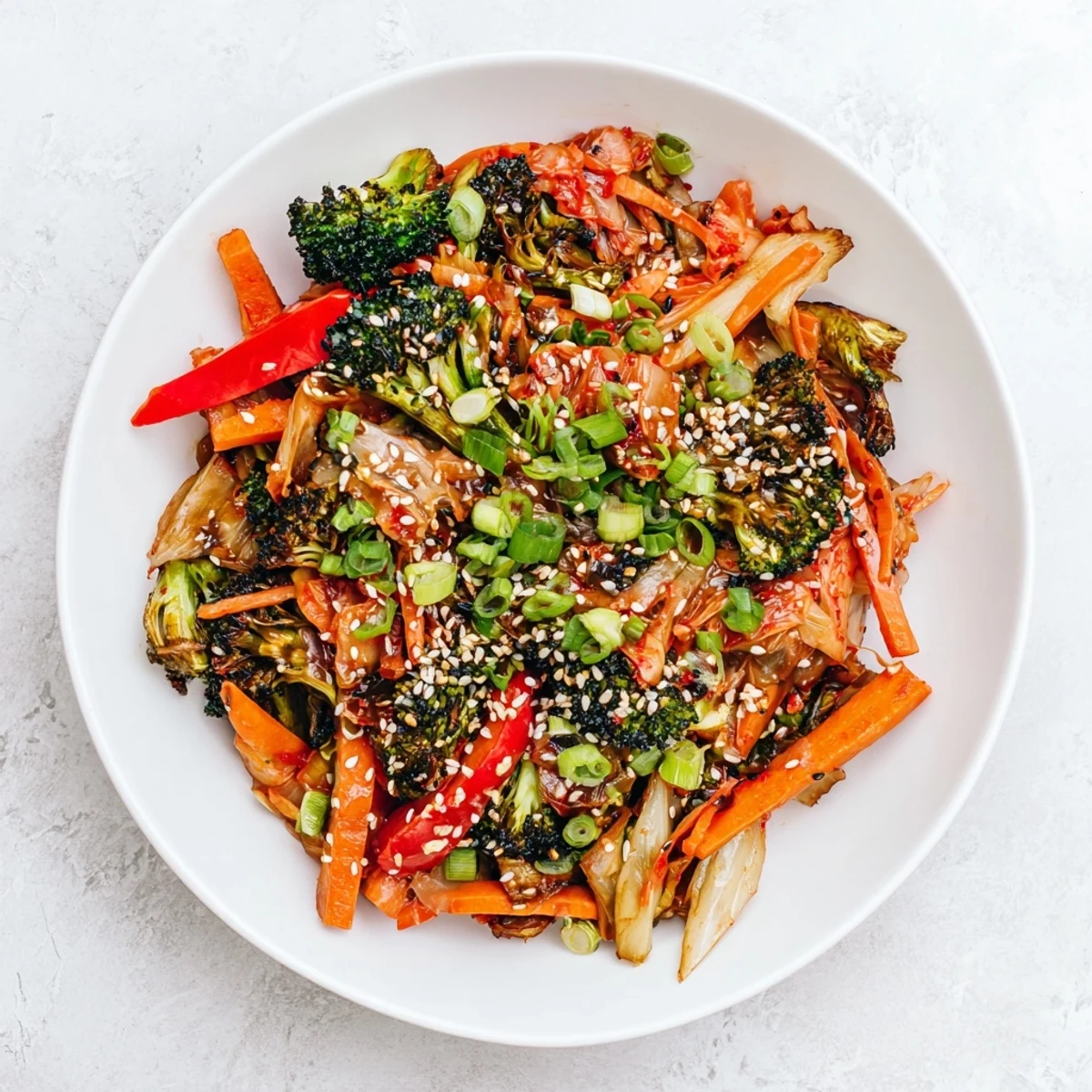 A close-up of Comforting Fermented Veggie Winter Stir-Fry, featuring vibrant broccoli, carrots, and sweet potato in a glossy, savory sauce topped with spicy kimchi.