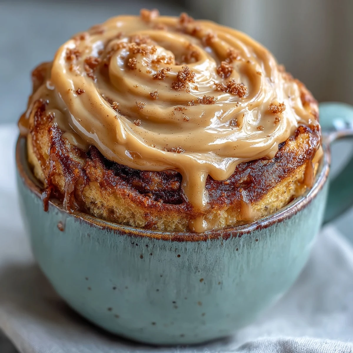 Gooey cinnamon-sugar swirl inside the High-Protein Cinnamon Roll Mug Cake topped with creamy white frosting.