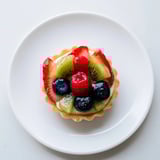 A close-up of beautifully arranged, bite-sized Mini Fruit Tartlets bursting with a variety of ripe fruits.