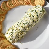 A close-up shot of an herb-coated cheese log, perfect for a party appetizer with crackers.