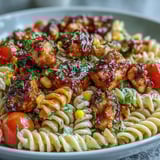 A chilled Honey BBQ Chicken Pasta Salad served at a summer picnic with fresh herbs and corn.