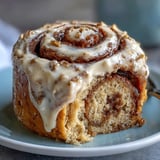 A warm High-Protein Cinnamon Roll Mug Cake microwaved to fluffy perfection, drizzled with tangy cream cheese frosting.