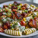 Creamy Honey BBQ Chicken Pasta Salad served in a clear glass bowl, garnished with chives and a drizzle of smoky dressing, perfect for easy potlucks.