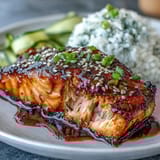 Glazed teriyaki salmon served over fluffy rice with bright edamame and cool cucumber slices in a balanced bowl.  