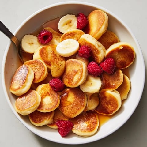 Delicious mini pancake cereal served warm in a bowl with milk.  