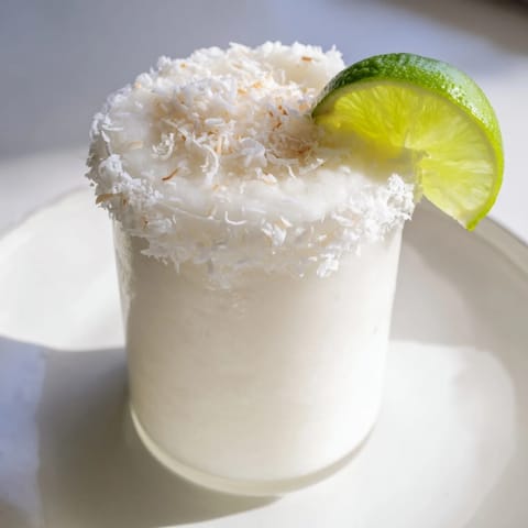 Creamy, icy White Christmas Margarita slush, garnished with lime and coconut—a holiday cocktail.