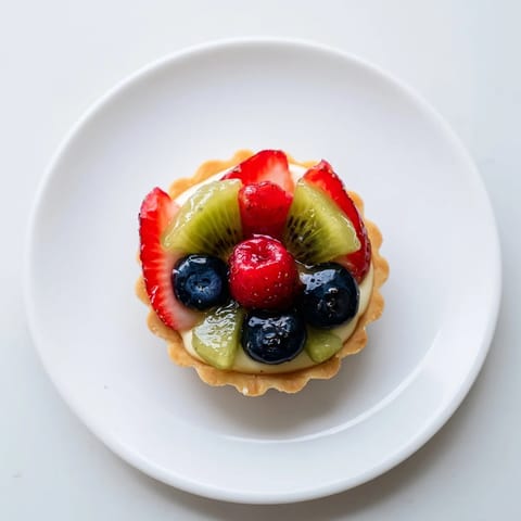 A close-up of beautifully arranged, bite-sized Mini Fruit Tartlets bursting with a variety of ripe fruits.
