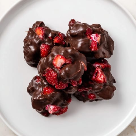 Bite into rich, chocolate-covered strawberry yogurt clusters, a delightful frozen treat.