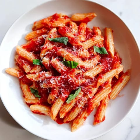 A close-up of perfectly cooked Microwave Bowl Pasta, tossed with fresh basil, smells delicious.