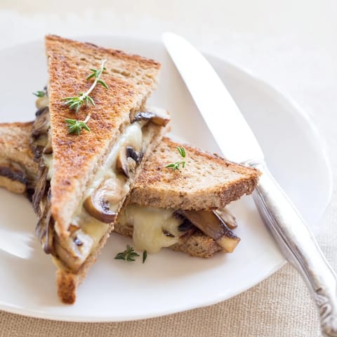 Sliced in half to reveal layers of earthy mushrooms and creamy Swiss cheese inside this gourmet grilled cheese sandwich.