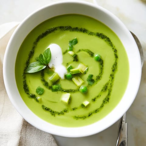 Vibrant spring Courgette, Pea and Pesto Soup with smooth texture and a dollop of crème fraîche, ideal for a light lunch.  
